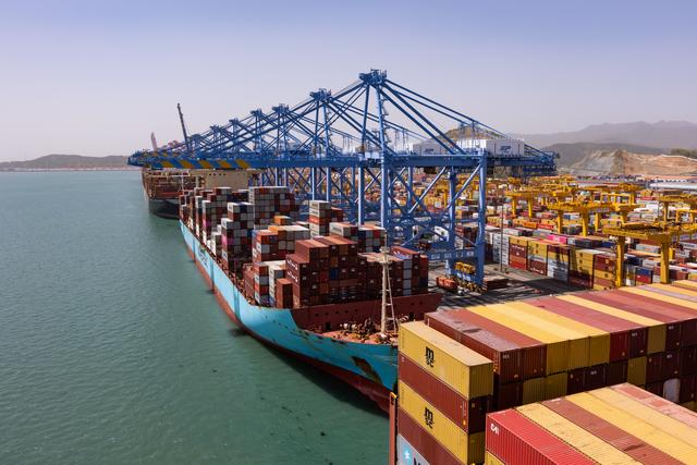 A large Container ship at the quay side with container cranes and container terminal visible in an aerial view of Busan terminal in South Korea