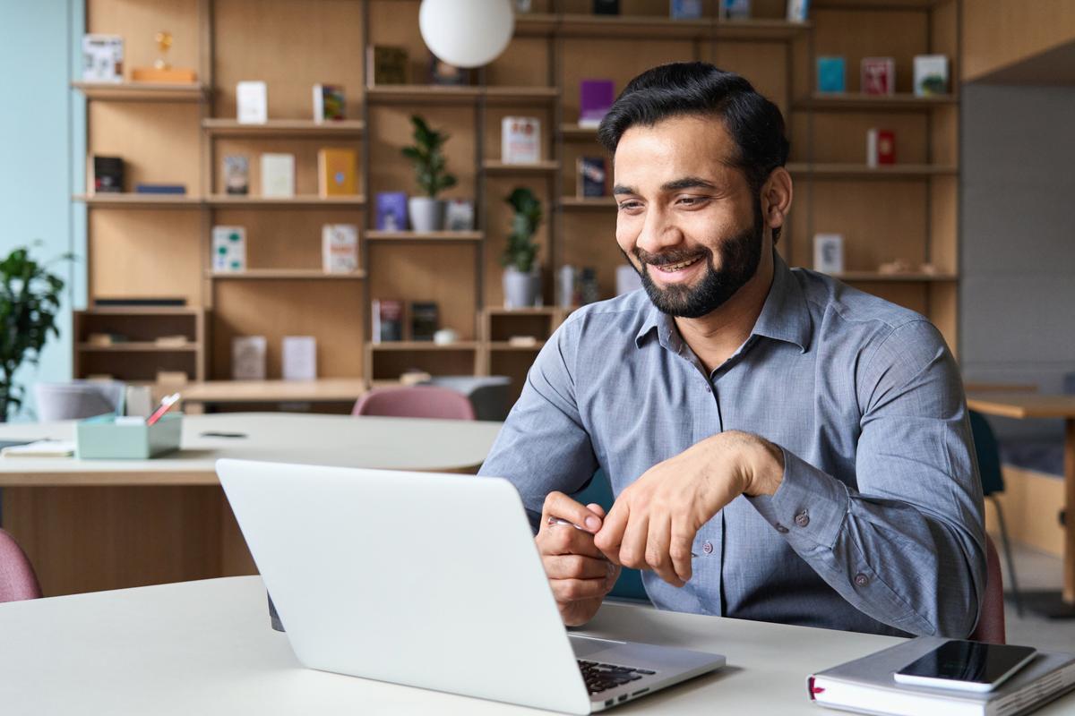 Man on his laptop in his office looking positive and engaged with the screen display.