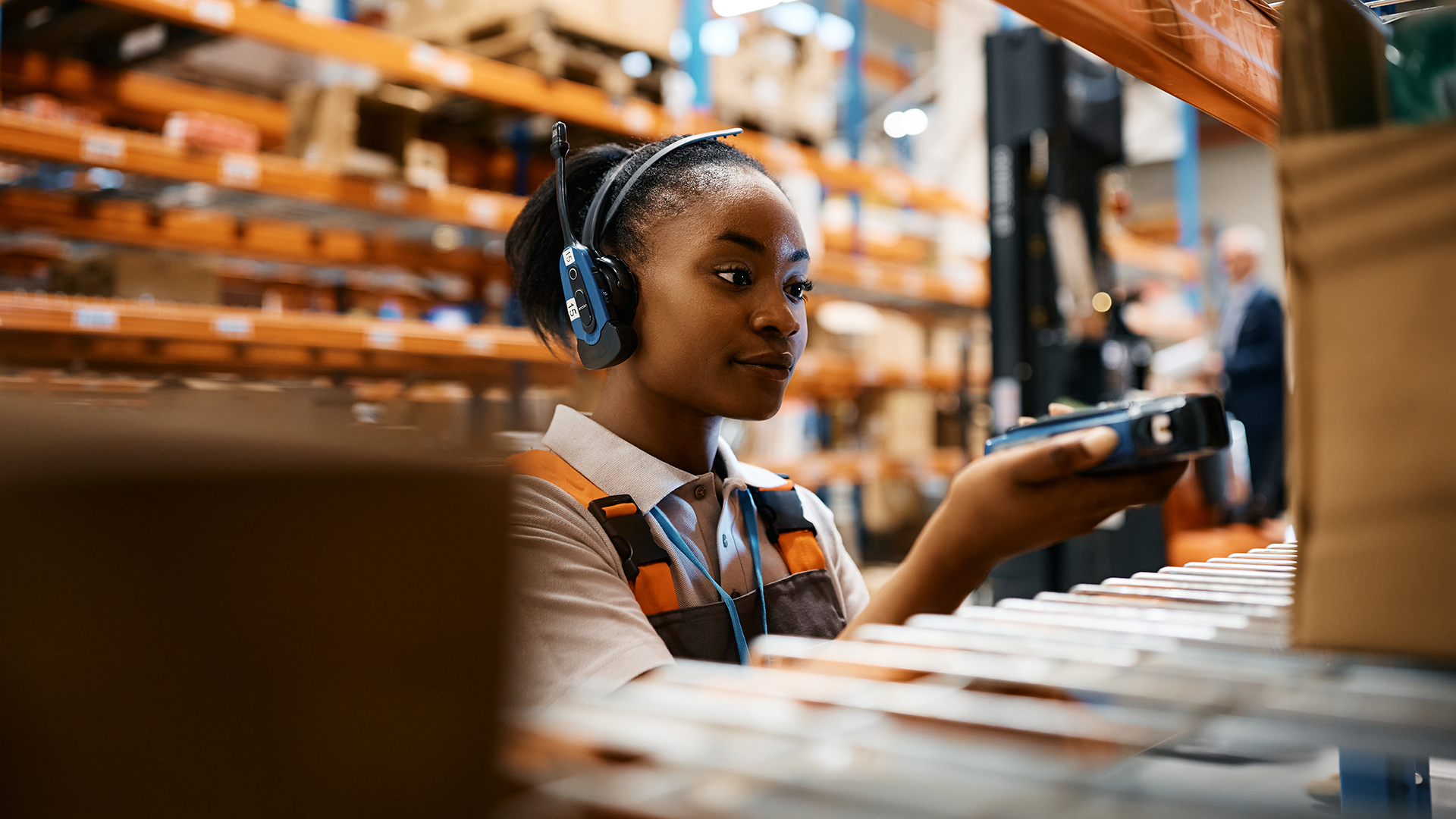 Why Choose Multi-Customer Warehousing? Worker using a handheld scanner with headset in a smart warehouse, emphasizing real-time inventory control in scalable tech logistics operations.
